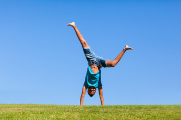 Outdoor portrait of a cute teenage black boy jumping over a blue