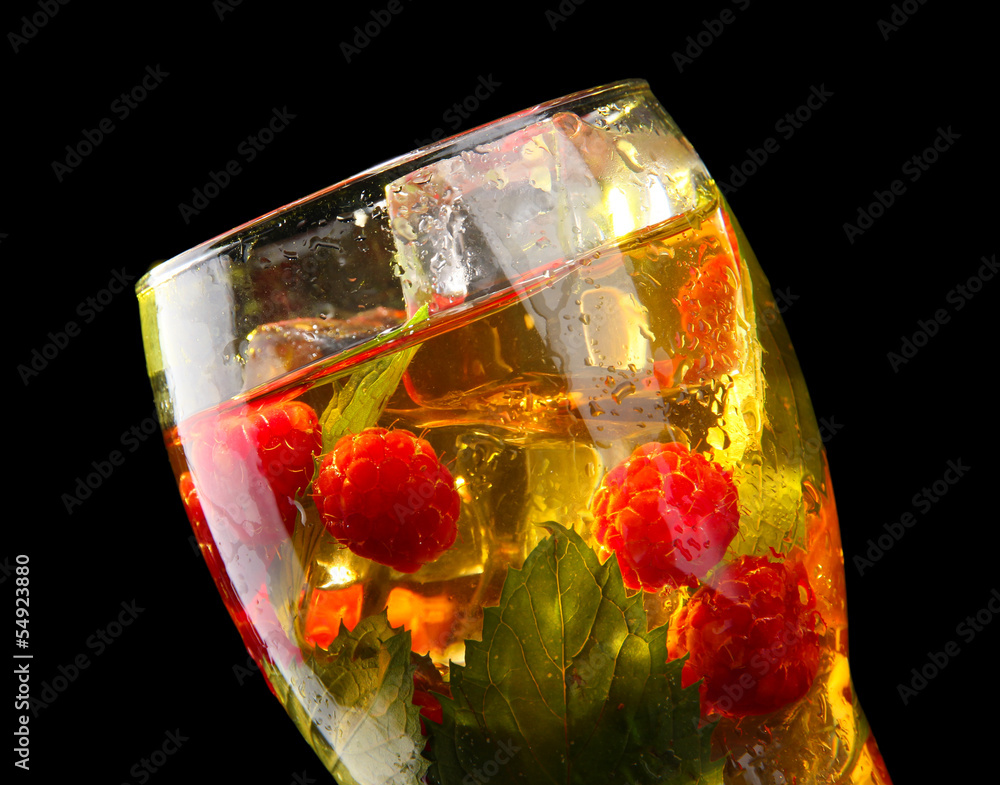 Iced tea with raspberries and mint on black background