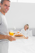 © WavebreakmediaMicro - Smiling man bringing breakfast in bed to his partner