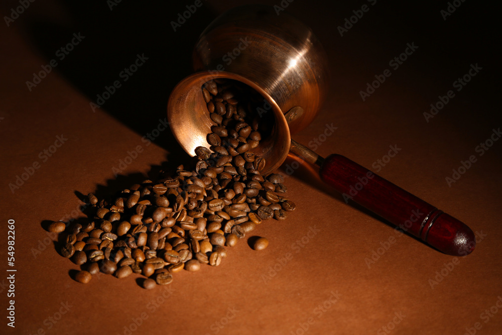 Coffee pot with coffee beans on brown background
