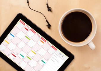 Wall Mural - tablet pc showing calendar on screen with a cup of coffee on a d