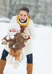 Wall Mural - Happy mother playing with baby in winter park