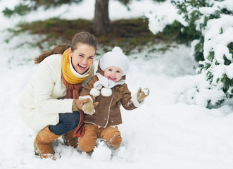 Wall Mural - Portrait of happy mother and baby in winter park
