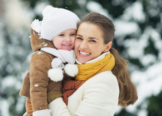 Wall Mural - Portrait of smiling mother and baby in winter park