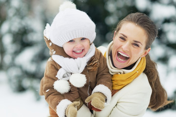 Wall Mural - Portrait of happy mother and baby in winter park
