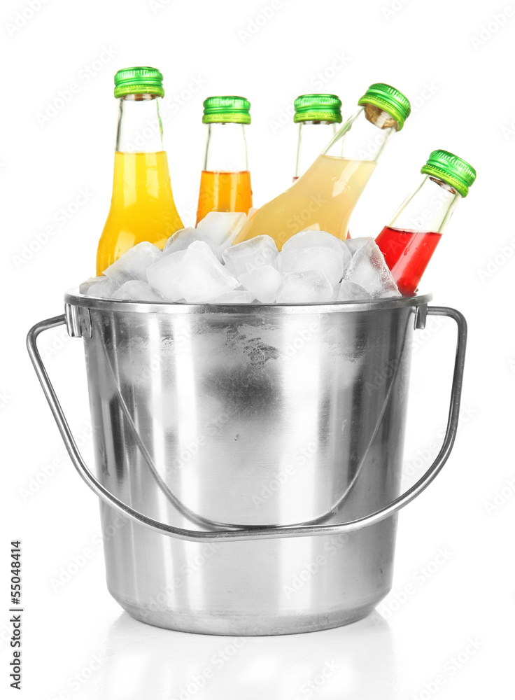 Bottles with tasty drinks in bucket with ice cubes, isolated