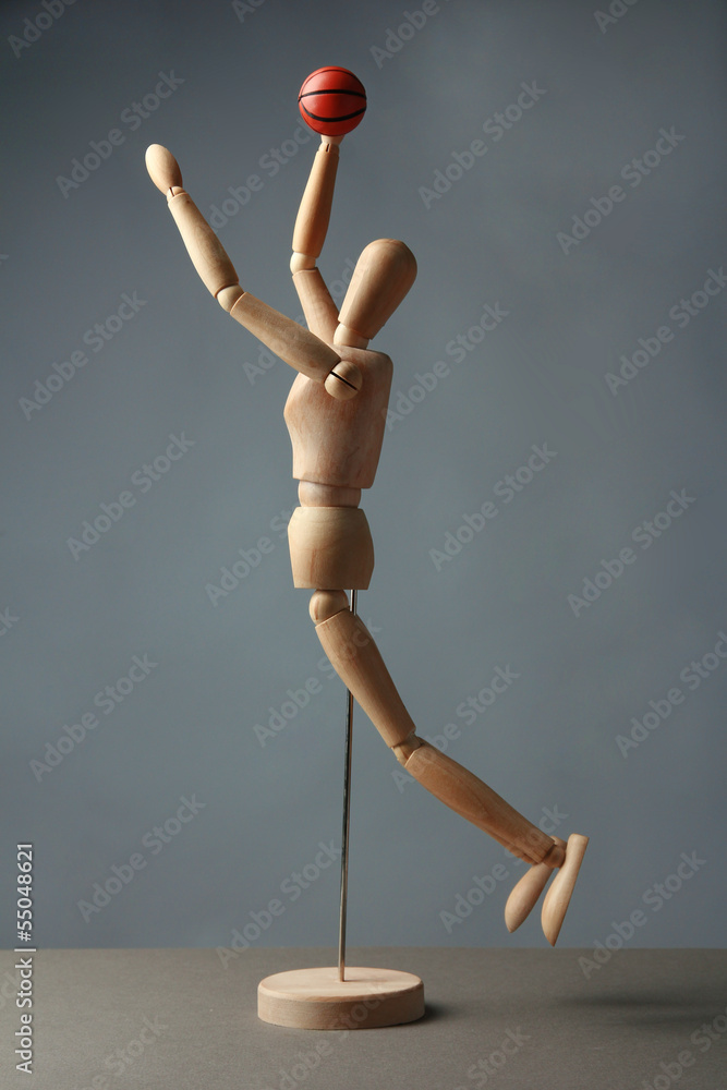 Wooden mannequin with basketball ball on grey background