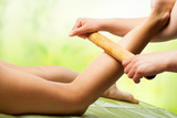 Fototapeta Sypialnia - Bamboo massage on female leg.