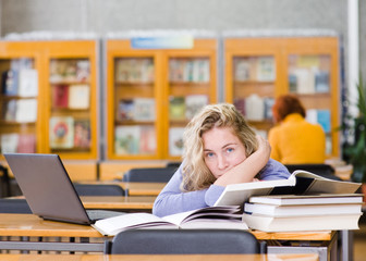 Wall Mural - tired student in a university library. looking at camera