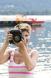 Young woman W34 on vacation takes a picture with her DSLR