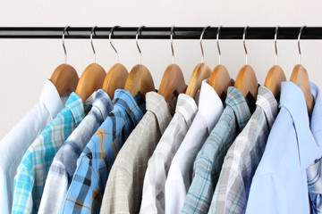 Wall Mural - Shirts with ties on wooden hangers on light background