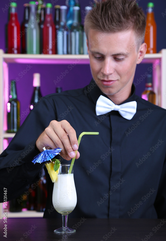 Portrait of handsome barman preparing cocktail, at bar
