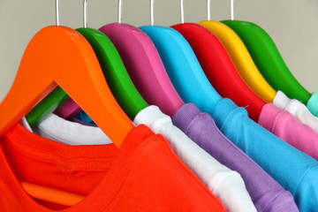 Different shirts on colorful hangers on grey background