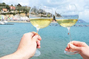 Wall Mural - Two wineglasses in the hands against the harbour of Portvenere,