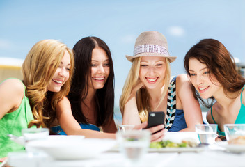 Canvas Print - girls looking at smartphone in cafe on the beach