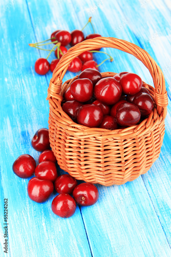 Cherry berries in wicker basket on wooden table close-up