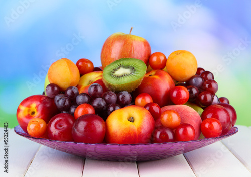 Naklejka na szybę Assortment of juicy fruits on wooden table, on bright