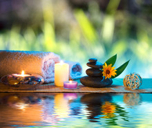 Three Candles And Towels Black Stones And Orange Daisy On Water