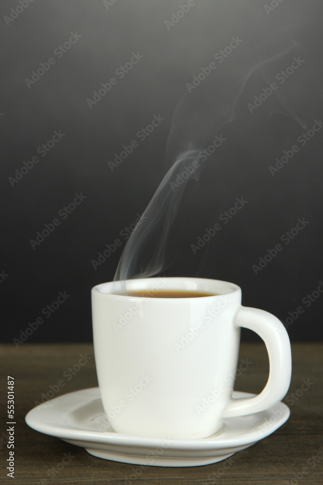 Cup of coffee on wooden table on black background
