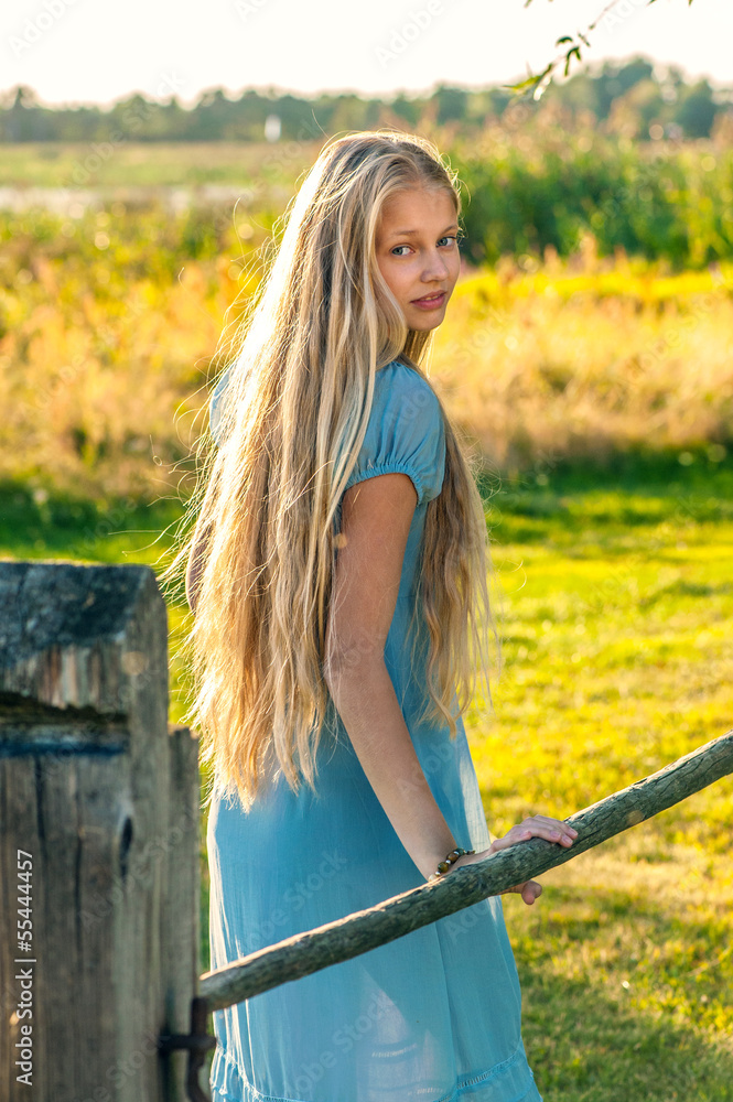 Beautiful young girl with long blond hair in blue dress in the c Stock ...