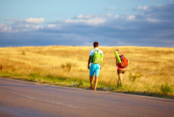 young people traveling hitchhiking. summer field