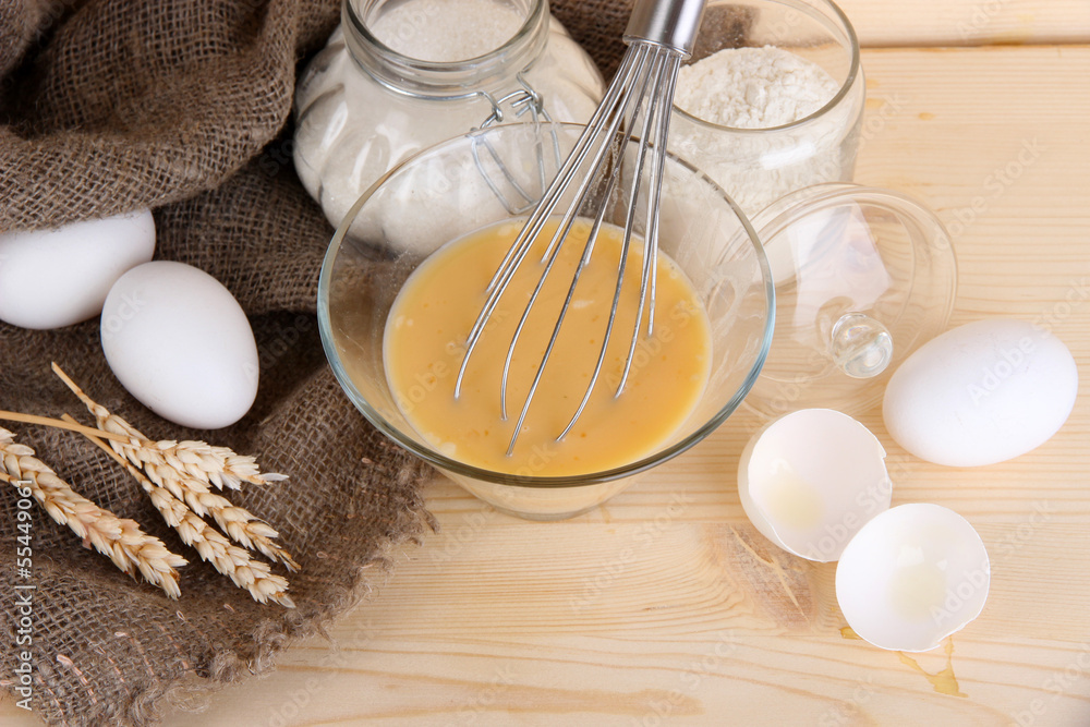 Ingredients for dough on wooden table on wooden background