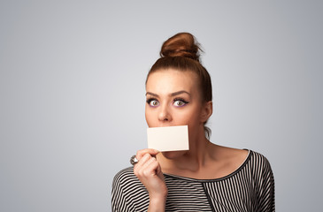 Cute girl holding white card at front of her lips with copy spac