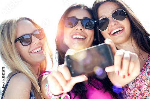 Fotografie, Tablou three friends taking photos with a smartphone