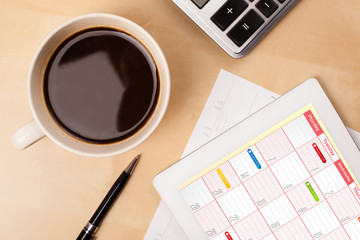 Wall Mural - tablet pc showing calendar on screen with a cup of coffee on a d