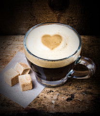 Poster - Coffee in glass with heart  foam and cane sugar on old wooden ba