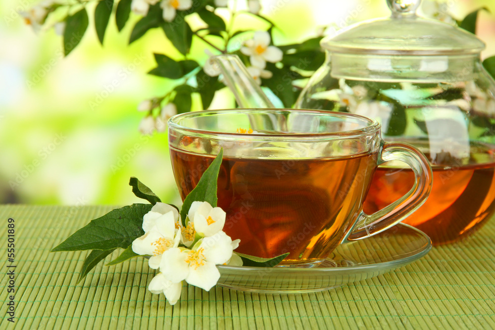 Cup of tea with jasmine, on bamboo mat, on bright background