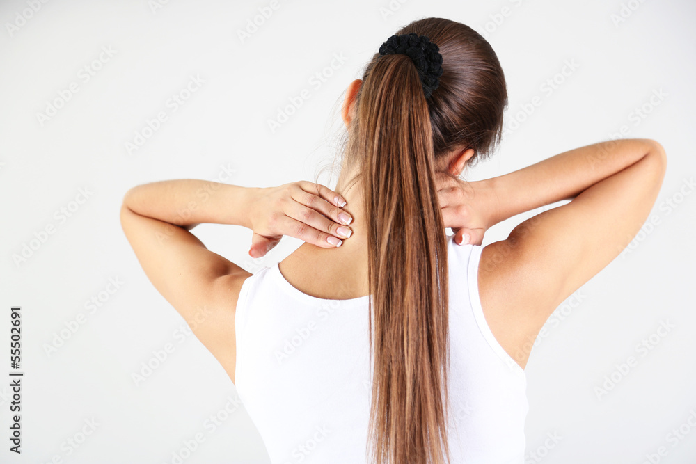 Young girl and pain in neck gray background