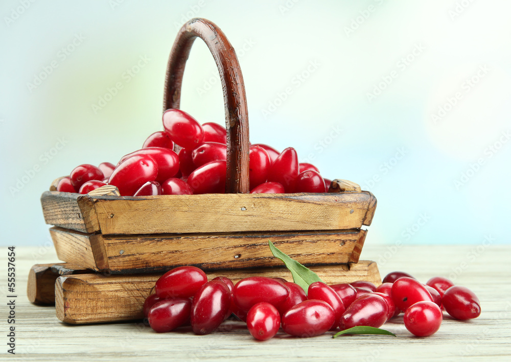Fresh cornel berries in basket on wooden table