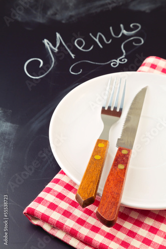 Board z aluminiowym obramowaniem Płyta, nóż i widelec na tablecloth na tle tablica