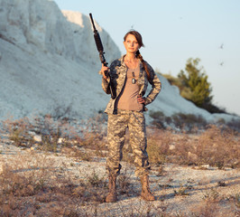 Young female soldier dressed in a camouflage with a gun in the l