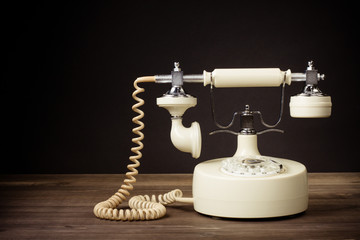 Fototapete - Vintage white rotary telephone on table against black background
