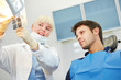 Zahnarzt zeigt Patient Karies auf Röntgenbild
