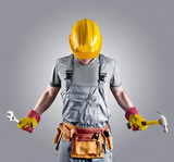 Fototapeta Zachód słońca - builder in a helmet with a hammer and a wrench