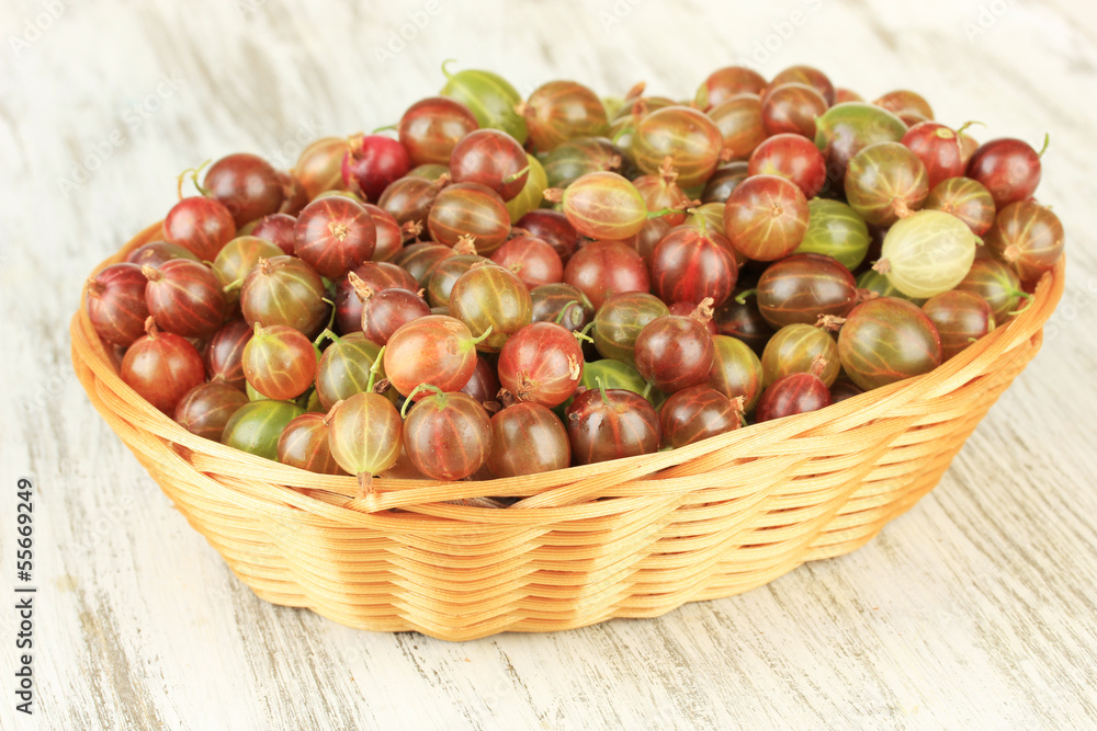 Fresh gooseberries in wicker basket on table close-up