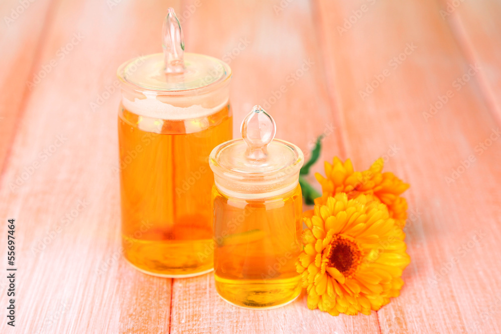 Medicine bottles and calendula flowers on wooden background