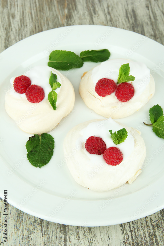 Tasty meringue cakes with berries on wooden table