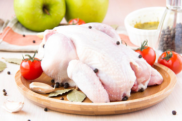 Raw whole small chicken with black pepper and herbs