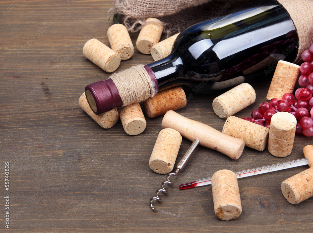 Bottle of wine, grapes and corks on wooden background
