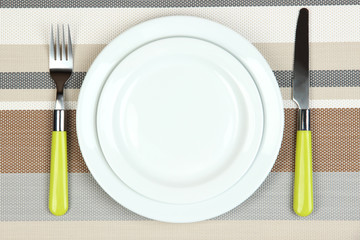 Knife, color plate and fork, on color background