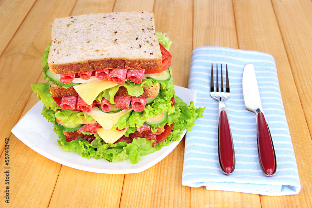 Huge sandwich on wooden table, on bright background