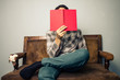 © LoloStock - man hiding his face behind book on old sofa