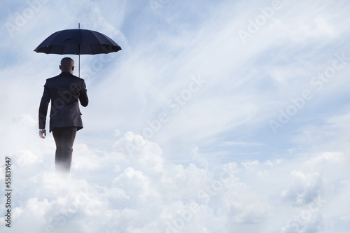 Fotoboard na płycie Biznesmen trzymając parasol i odejść w zjawiskowe chmury