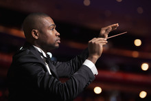 Young Conductor With Baton Raised At A Performance 