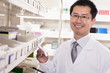© xixinxing - Pharmacist taking down and examining prescription medication in a pharmacy, looking at camera