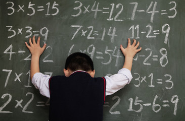 Schoolboy in front of blackboard with hands on chalkboard